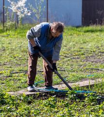 A woman works with a hoe in the garden in the spring