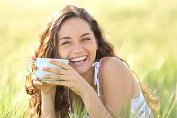  Happy woman laughing looking at you holding coffee cup in nature © Antonioguillem