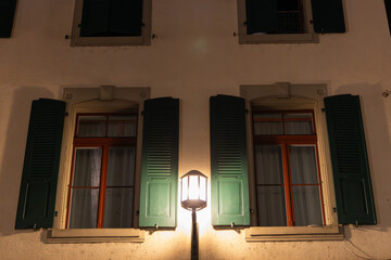 windows in the building with a gaslamp lighning up the street