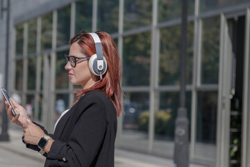 business woman walking through the city using mobile devices and headphones