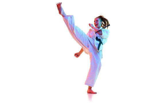 Side view portrait of karate fighter, taekwondo master shouting and training in action isolated over white studio background. Concept of professional sport, recreation, art, hobby, culture. Copy space