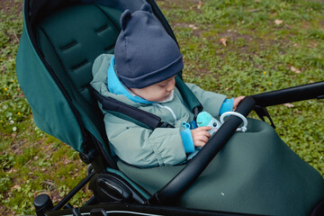 Surprised child in stroller in spring park