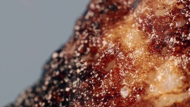 An ignited meal burns and melts in the flame, blows bubbles and boils in the smoke, isolated on the grey background. A red hot dish is undergoing intensive frying and heat treatment. Close up.