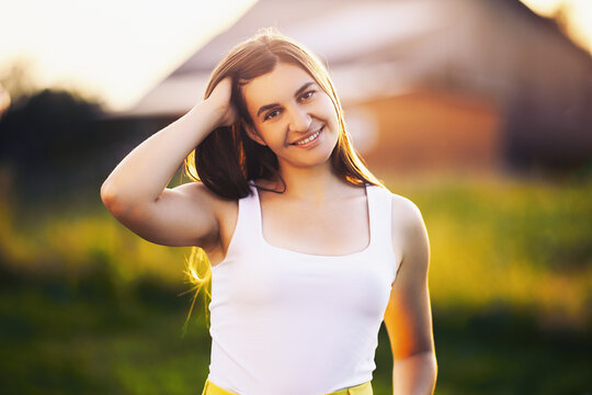 Perfect teeth of young Caucasian woman with perfect smile at setting sun against blurred background of rural landscape.