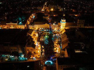 Aerial night shot of city during Christmas, winter and christmas decorations on square. Chistmas market during holiday season in small city.