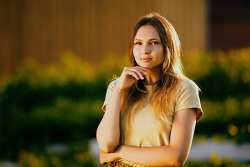 Half-length portrait of woman taken during golden hour in countryside, mysterious gaze of young white female at sunset.