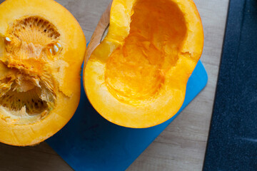 Eating self-grown vegetables. Cooking bright orange pumpkin lying on a purple cutting board.