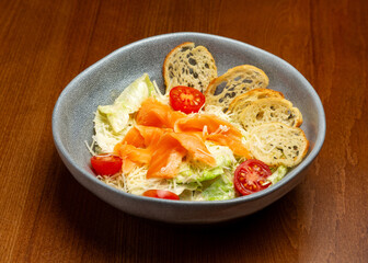 Caesar salad with salmon in a plate.