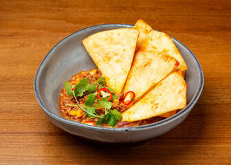 Mexican dish with minced meat, corn, beans and chips in a plate.