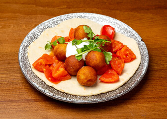 Cheese balls with tomatoes on flatbread in a plate.