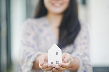Hands of young woman holding model house, real estate insurance and banking concept.