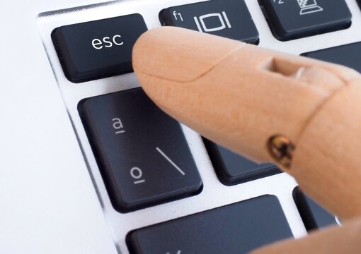 Wooden finger pressing esc button on computer keyboard