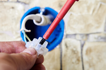 Plastic electrical connector or terminal blocks, an electrician tightens mounting screw holding an...