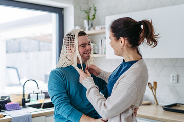 Young man with Down syndrome and his mom being funny, have mash net bag on head.