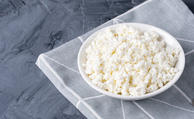 Cottage cheese in a white bowl on a grey background