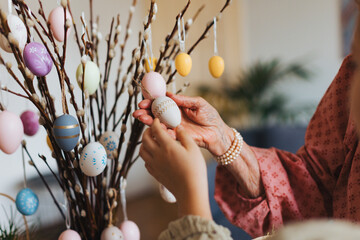 Close up of decorating pussy willows branches, putting easter eggs on them.