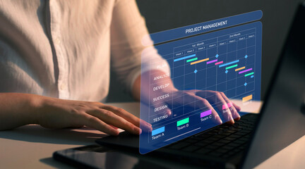 Project manager working on laptop and updating tasks and milestones progress planning with Gantt chart scheduling interface for company on virtual screen. Business Project Management System.	
