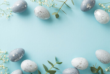 Festive Easter composition: Directly top view of beautiful grey eggs, gypsophila blooms, and eucalyptus branches arrayed on a pale blue ground, with a vacant spot for textual content or advertising - obrazy, fototapety, plakaty