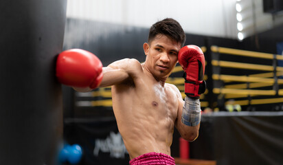 Male athlete boxing competition in ring. Asian ethnic man punch fighting in kickboxing exercise in fitness gym. Boxing is fighter sport training need body strength and power fist to knockout.
