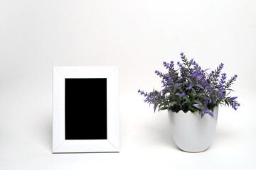 empty photo frame next to a flower pot on a white background
