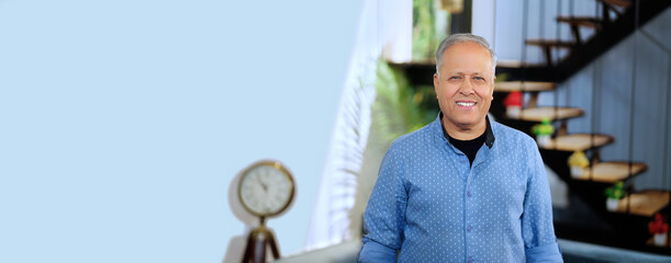 Happy Indian Asian old elder man smiling coach look cam pose video indoor house home grey haired older male trainer staff agent worker boss CEO fold arm cross hand. Head shot copy space empty text 