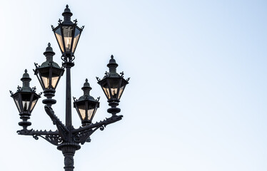 A lighting pole with antique lanterns against the sky.