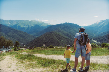 Fototapeta na wymiar Travel hiking with children. Man with sons enjoying beautiful view of Caucasus Mountains 