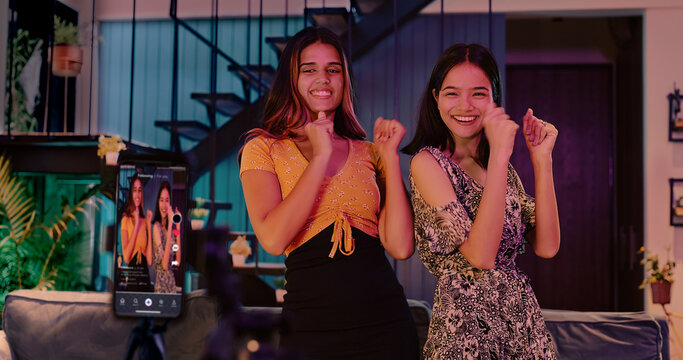 Indian Asian young adult gen z girls couple love record reel dance moves use mobile phone cam enjoy joy room teen female make trendy song music fun content blog video social media stories indoor house