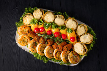 assorted meat rolls, appetizer. on a black wooden background