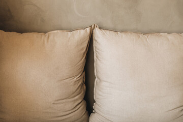 Pillows made of beige natural textile. Minimalistic details in the interior