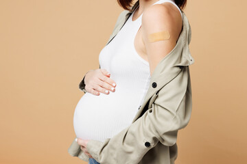 Cropped close up young pregnant woman future mom wearing grey shirt vaccine adhesive plaster with...