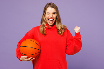 Young exultant jubilant fun woman fan wear red hoody cheer up support basketball sport team hold in...