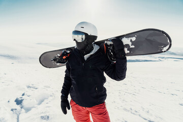 Snowboarder holding board on snowy mountain, ready for an adrenaline-filled descent in a winter...