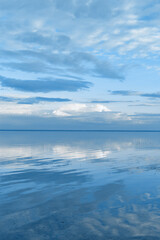 White blue clouds over lake, symmetric sky and water background, cloudscape on lake. Nature abstract, cloudy sky reflected on water, calm tranquil concept, aesthetic panoramic view