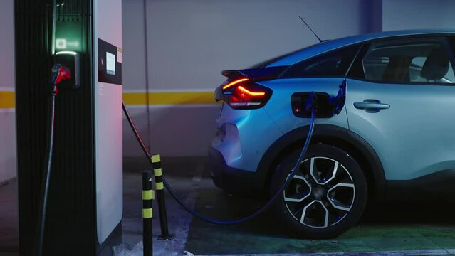 Electric car connected wire on ev charging station in modern parking. Alternative fuel vehicles. Environmentally friendly transportation