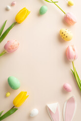 Immerse yourself in Easter season with this top view vertical arrangement of colorful eggs, bunny ears, blooming tulips on delicate pastel background. A vacant frame awaits your message or advert