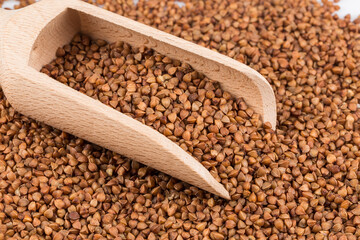 Uncooked buckwheat on wooden spoon