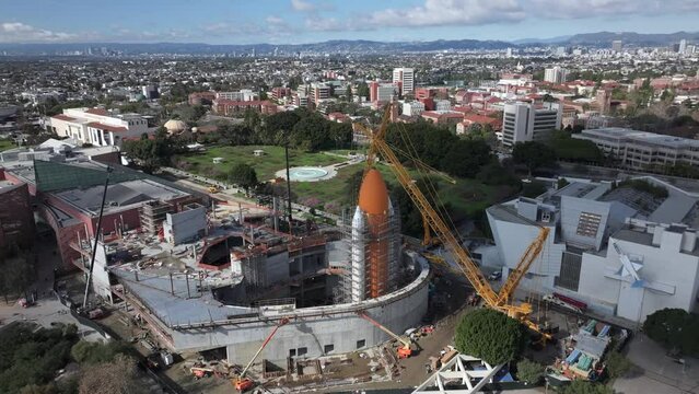 Display of Space Shuttle at Los Angeles museum under construction scaffolding, aerial orbit