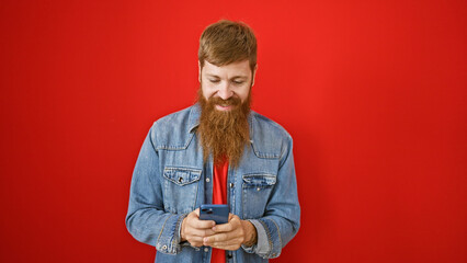 Handsome young redhead man, brimming with happiness, confidently typing away messages on his...