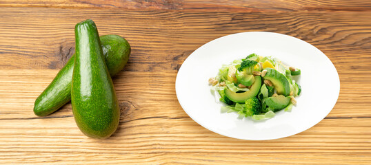 Green Salad with Avocado, Cucumber and Nuts on White Plate