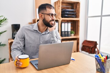 Young hispanic man business worker using laptop drinking coffee at office