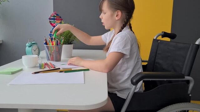 Child in wheelchair coloring artwork and muscle development skills. Special way of life of children with disabilities