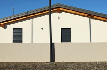 Black pole and gray concrete fence with white new house facade with gray windows on behind. Porphyry sidewalk in front. Background for copy space.