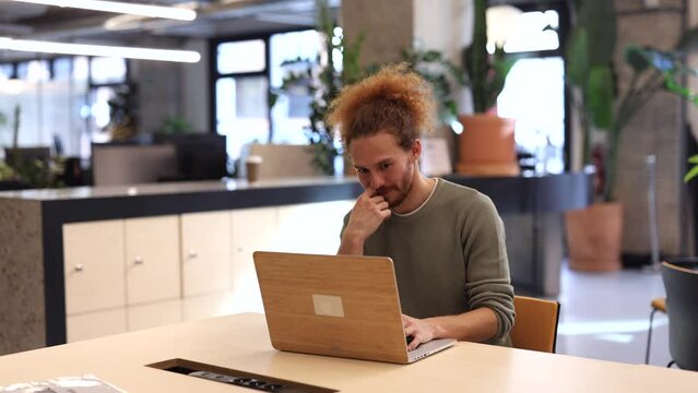 happy and proud creative Hispanic business man working on a laptop in an open plan office