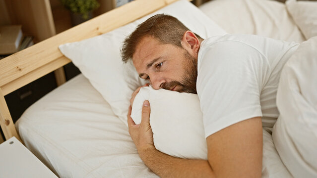 Worried middle-aged man with grey hair lying in bed indoors, portraying anxiety or insomnia - Powered by Adobe