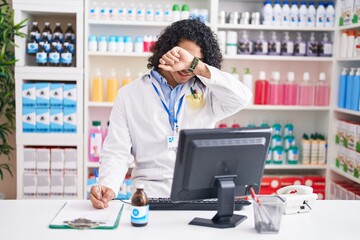 Hispanic man with curly hair working at pharmacy drugstore smiling cheerful playing peek a boo with...