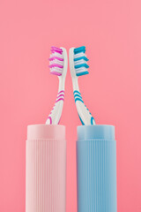 Two toothbrushes on a pink background from a low angle view. Vertical shot.