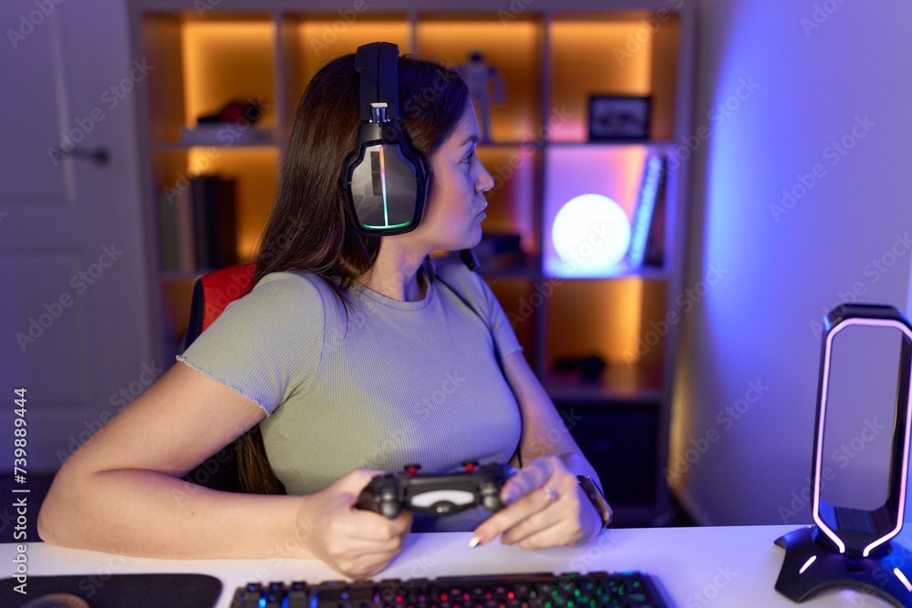 Sticker Beautiful brunette woman playing video games wearing headphones looking to side, relax profile pose with natural face and confident smile.