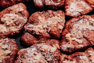 Delicious sweet freshly baked croissants with almonds and powdered sugar