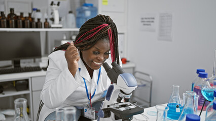 Smiling, confident african american woman scientist rejoicing in tech-focused lab, celebrating...